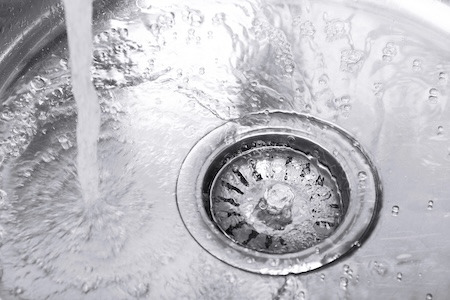Plumber performing professional drain cleaning in a Collierville, TN kitchen